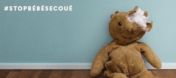 Un ours en peluche avec un pansement avec le # de la campagne du syndrome du bébé secoué