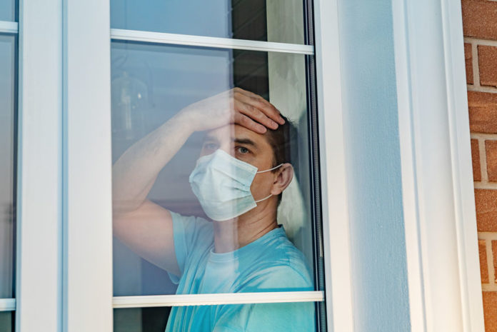Un homme avec un masque regarde par la fenêtre