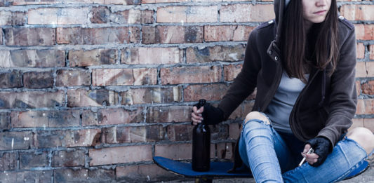 Jeune fille assise sur un skate entrain de fumer et boire