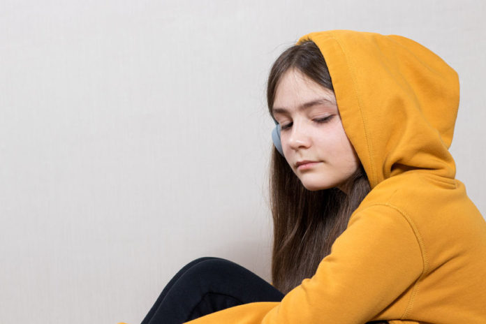 Jeune fille triste portant une sweat à capuche jaune