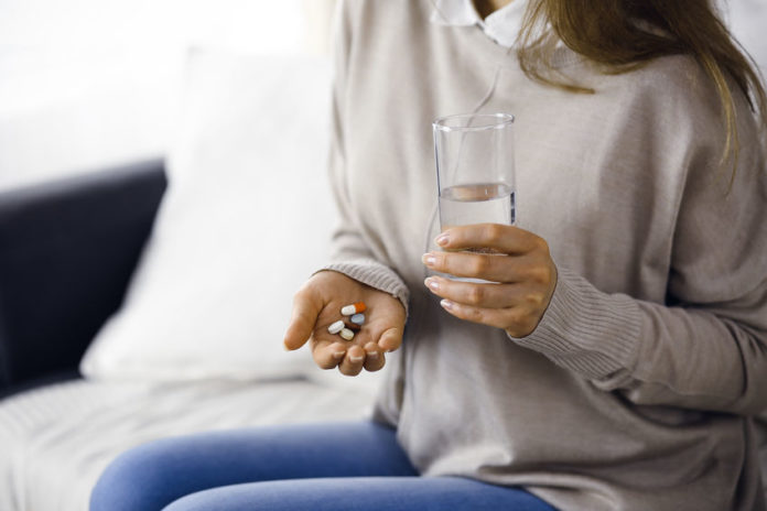 Femme prenant des médicament avec un verre d'eau