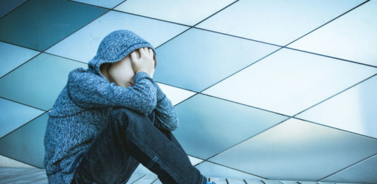 Adolescent triste se tenant la tête dans les mains